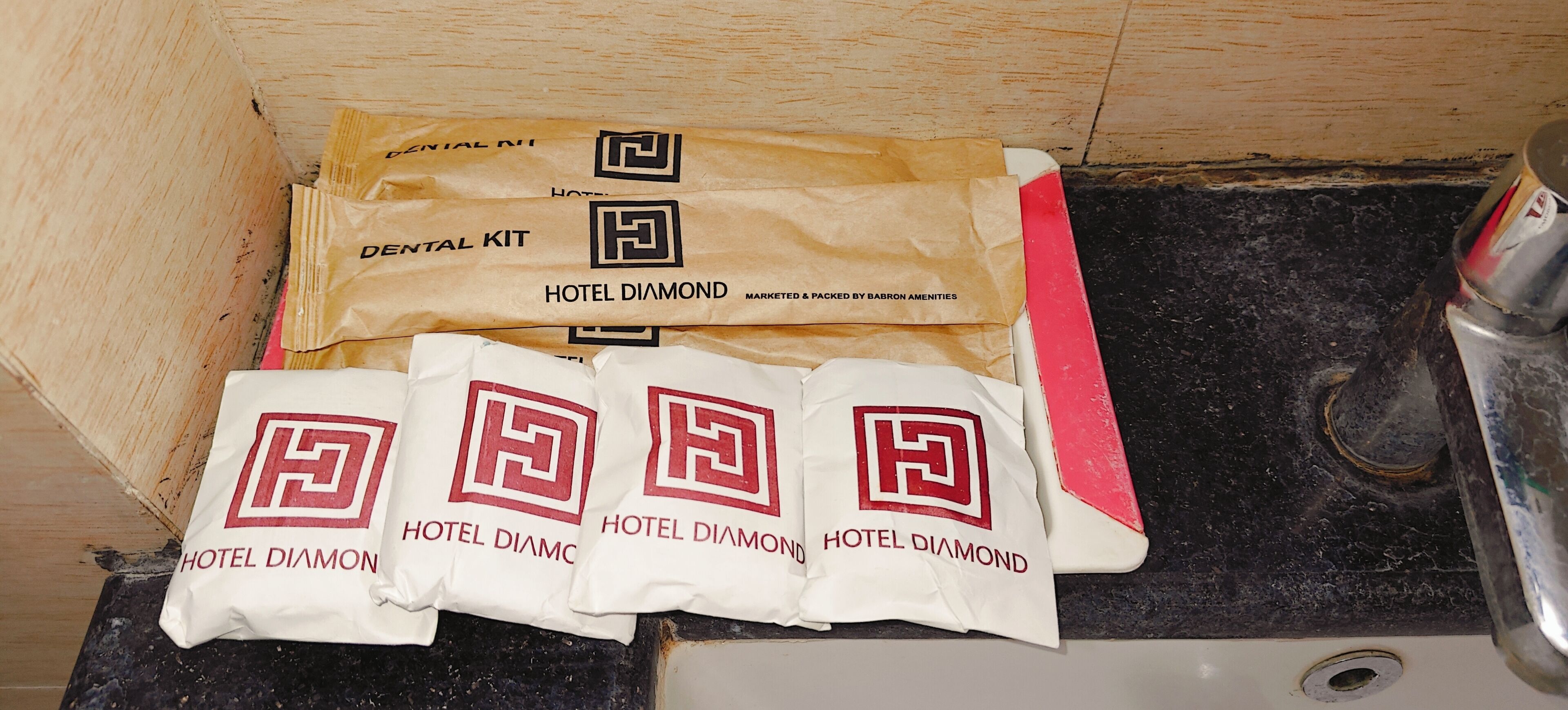 En trälåda som innehåller ett set med hotellartiklar och flera kuddar med Hotel Diamonds logotyp.