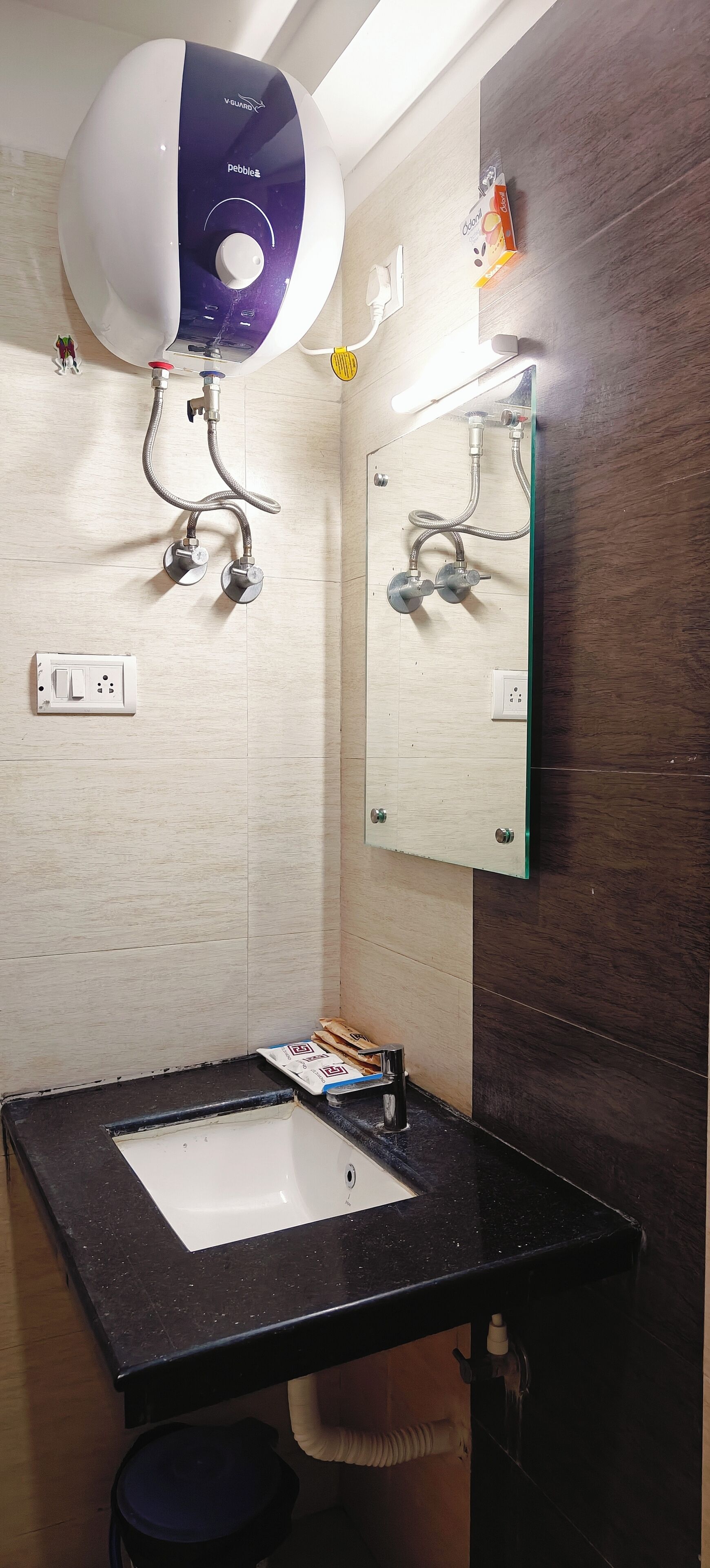 A bathroom with a modern design, featuring a large mirror, a sink, and a handheld showerhead mounted on the wall.