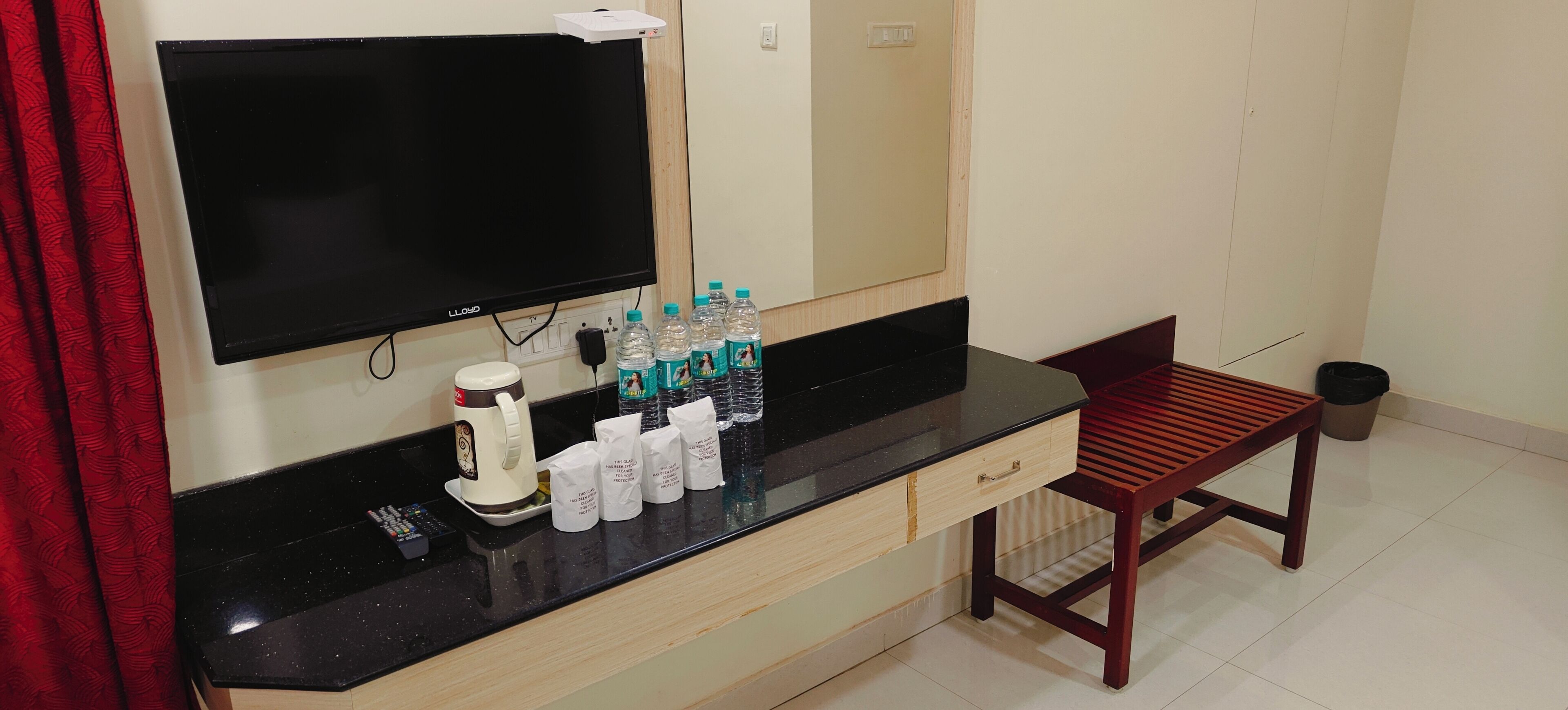 A hotel room with a black countertop, a coffee maker, bottled water, and a wooden chair.