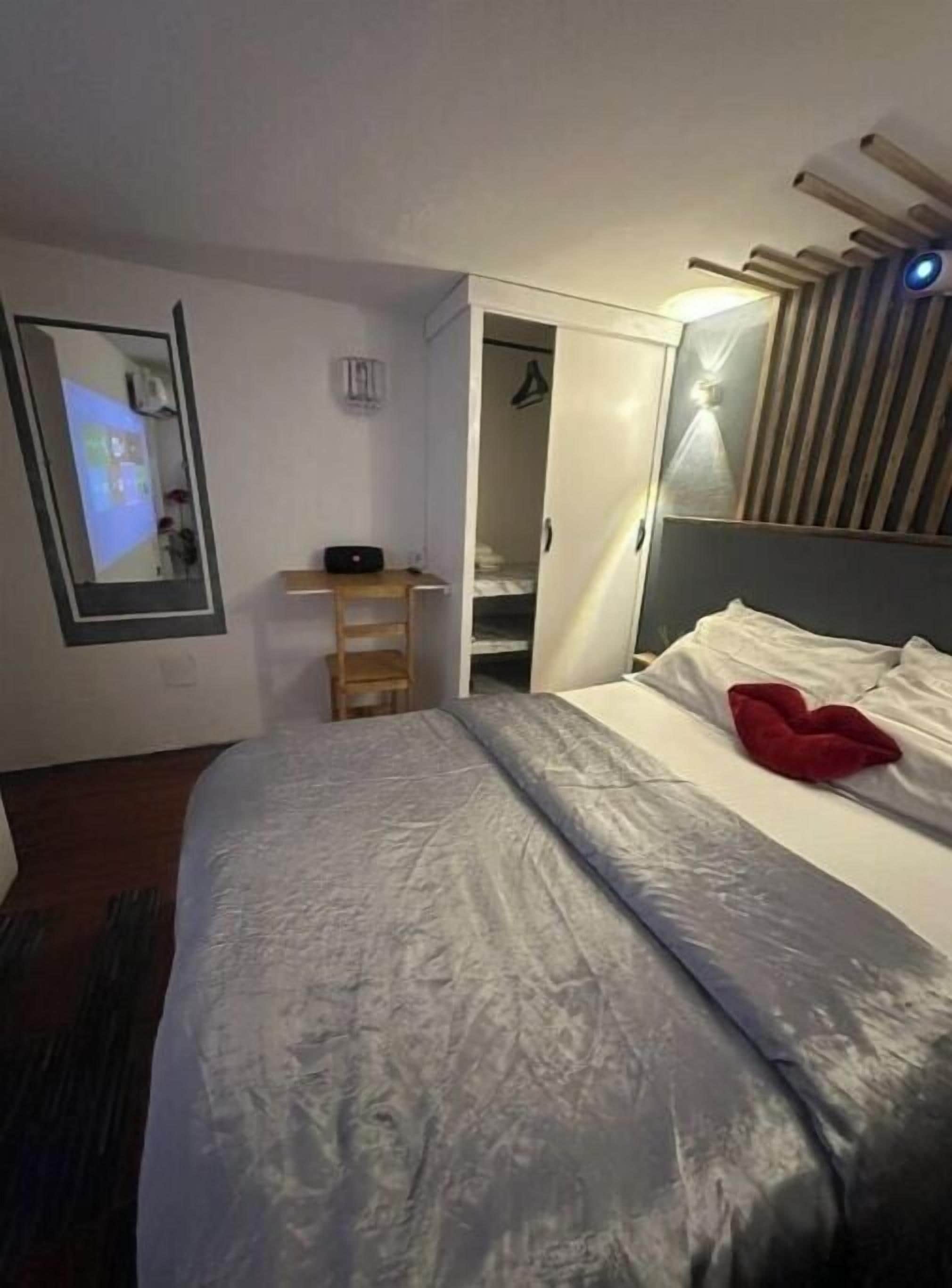 Un dormitorio con cama, escritorio, armario y espejo.