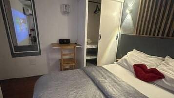 Un dormitorio con cama, escritorio, armario y espejo.
