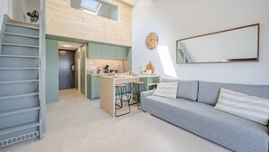 En moderne lejlighed med et køkken, spiseplads og en stue med sofa og et stort spejl.