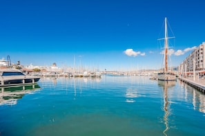 Un port de plaisance avec des bateaux amarrés, un ciel dégagé et des bâtiments en arrière-plan.