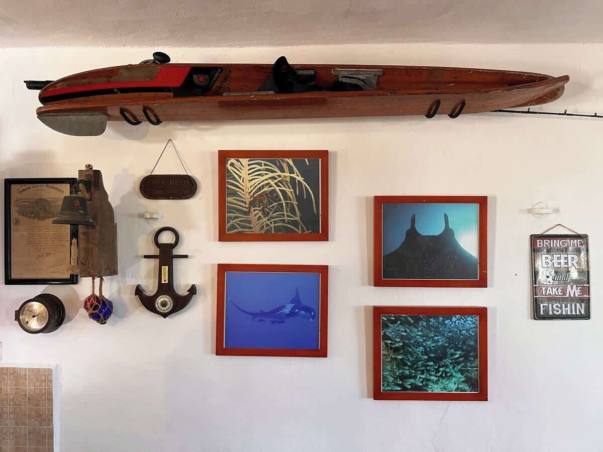 Un mur orné d’un bateau en bois, de tableaux encadrés, d’une cloche et d’une enseigne.