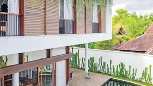 Ein zweistöckiges Gebäude mit Pool, Sitzgelegenheiten im Freien und einer Gartenmauer.