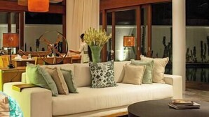 Ein modernes Wohnzimmer mit einem weißen Sofa, mehreren Kissen, einem Couchtisch und einer Vase mit Blumen.