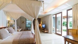 Ein Schlafzimmer mit Baldachinbett, Fernseher und Blick ins Freie.