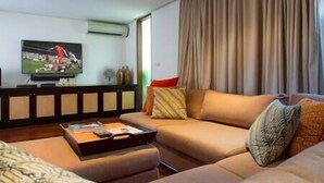 Ein modernes Wohnzimmer mit einer Couch, einem Couchtisch und einem an der Wand befestigten Flachbildfernseher.