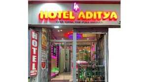 The entrance of Hotel Aditya with a neon sign, a staircase, and indoor plants. - Hotel Aditya (Varanasi)