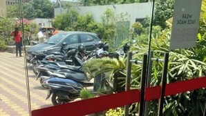 A gated entrance with potted plants and parked motorcycles. - Hotel Aditya (Varanasi)