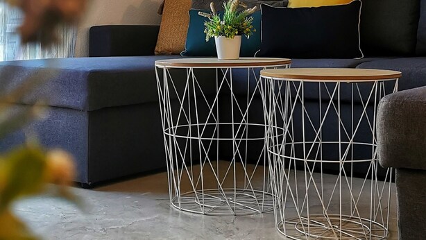 Una sala de estar moderna con un sofá oscuro, una mesa de centro y obras de arte en la pared.