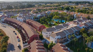 Vista aérea de una zona residencial con casas escalonadas, una carretera y una piscina grande.