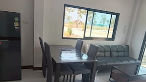 Un salon moderne comprenant une table à manger, des chaises, un canapé et une grande fenêtre donnant sur l’extérieur.