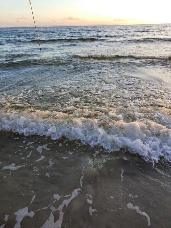 A beach with waves crashing onto the shore, a fishing rod in the water, and a clear sky. - A&B Beach Villa At VK (Mai Rut)