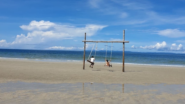 Une plage avec une balançoire et un ciel dégagé.