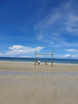 A beach with a swing set and a clear sky.