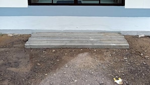 Un bâtiment doté de grandes portes vitrées et d’un seuil en béton menant à l’entrée.