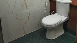 A bathroom with a toilet, marble walls, and green floor tiles. - Charming 2BR duplex house rooftop Oasis (Colombo)
