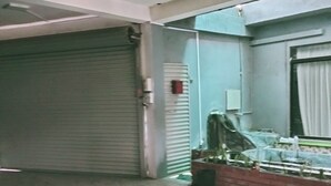 A room with a closed shutter door, a ceiling fan, and a window with a view of parked cars outside. - Charming 2BR duplex house rooftop Oasis (Colombo)