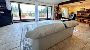 Un salon spacieux avec un grand canapé, une cheminée et une vue sur l’extérieur grâce à une porte-fenêtre coulissante.