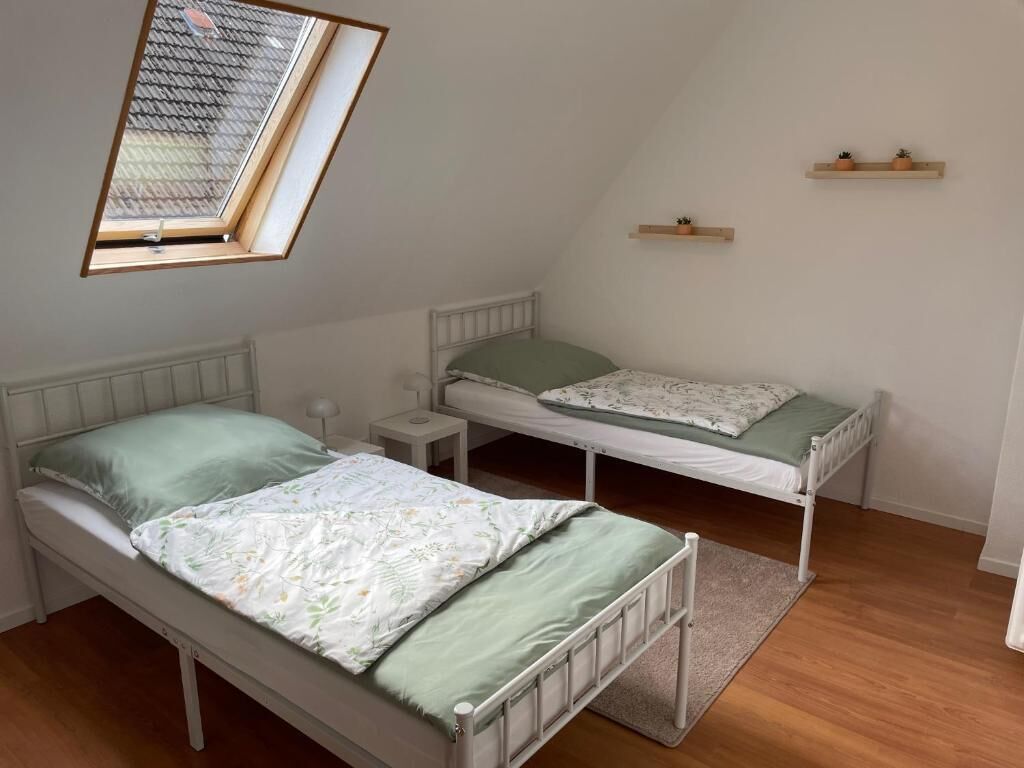Un petit appartement d’une seule pièce, comprenant deux lits, une lucarne et une petite fenêtre.