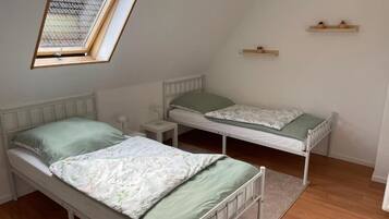 Un petit appartement d’une seule pièce, comprenant deux lits, une lucarne et une petite fenêtre.