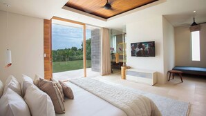 A modern bedroom with a large bed, a TV, and a view of a garden. - The Iman Villa by Elite Havens (Kabupaten Badung)