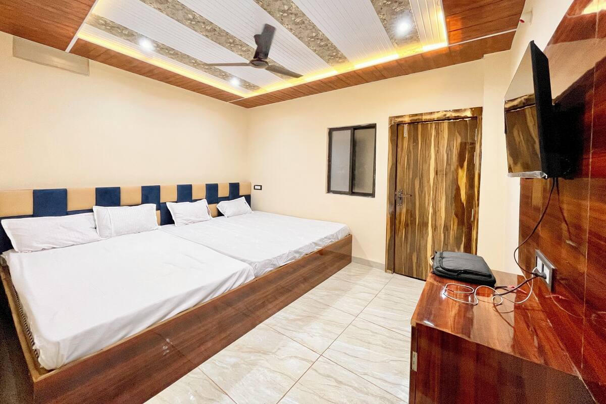 A bedroom with a double bed, a wooden headboard, a ceiling fan, a TV mounted on the wall, and a wooden door.