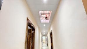 A corridor with white walls, wooden doors, and a marble floor. - Shree Sawariya Palace (Ujjain)