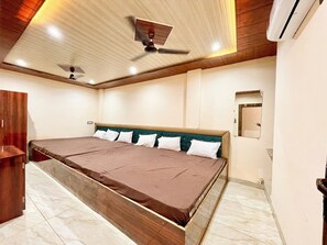 A bedroom with a large bed, wooden ceiling, and a ceiling fan. - Shree Sawariya Palace (Ujjain)