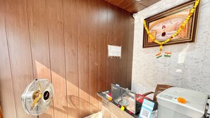 A room with wooden paneling, a fan, a desk with a computer, and a wall-mounted sign. - Shree Sawariya Palace (Ujjain)