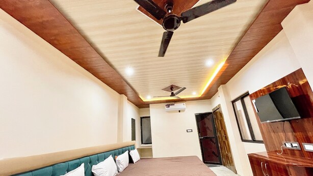 A bedroom with a bed, a ceiling fan, an air conditioning unit, a wardrobe, and a television. - Shree Sawariya Palace (Ujjain)
