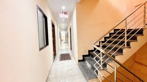 A hallway with a marble floor, a staircase with metal railings, and a ceiling with recessed lighting. - Shree Sawariya Palace (Ujjain)