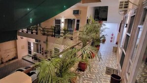 A multi-level interior with a central staircase, potted plants, and a tiled floor. - Saini Guest House (Gurdaspur)