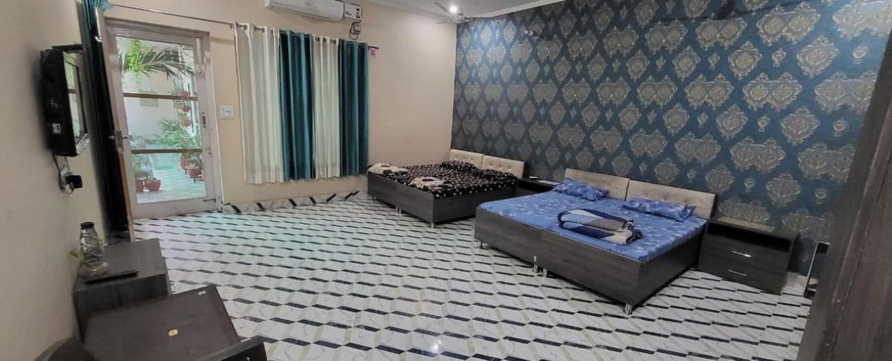 Quarto com duas camas, televisão e papel de parede estampado.