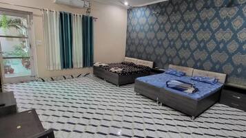 Quarto com duas camas, televisão e papel de parede estampado.