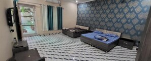 A bedroom with two beds, a TV, and a patterned wall. - Saini Guest House (Gurdaspur)