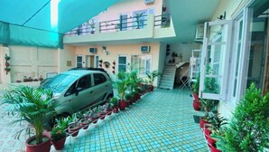 A multi-level building with a car parked in the courtyard, surrounded by potted plants. - Saini Guest House (Gurdaspur)