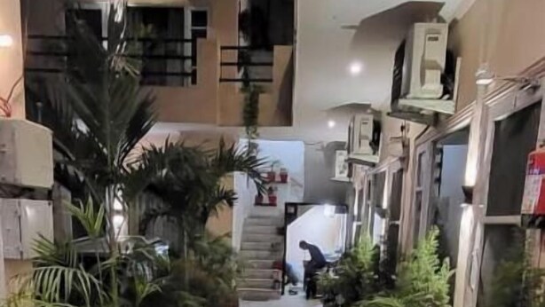 A corridor with tiled flooring, potted plants on both sides, and air conditioning units mounted on the walls. - Saini Guest House (Gurdaspur)