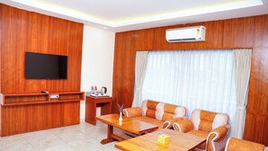 Una sala de estar moderna con un panel de pared de madera, un televisor de pantalla plana, un sofá, una mesa de centro y una mesita auxiliar con una tetera.