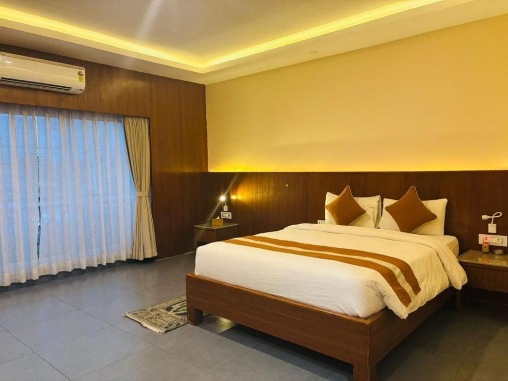 Habitación de hotel con una cama grande, cabecero de madera y una mesita de noche con lámpara.