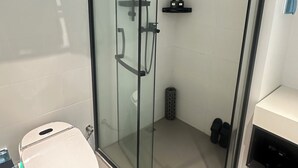 Un baño moderno con ducha envuelta en vidrio, inodoro y lavamanos.