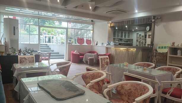 Un restaurante con terraza, una escalera que sube a una plataforma y una cocina visible a través de las ventanas.