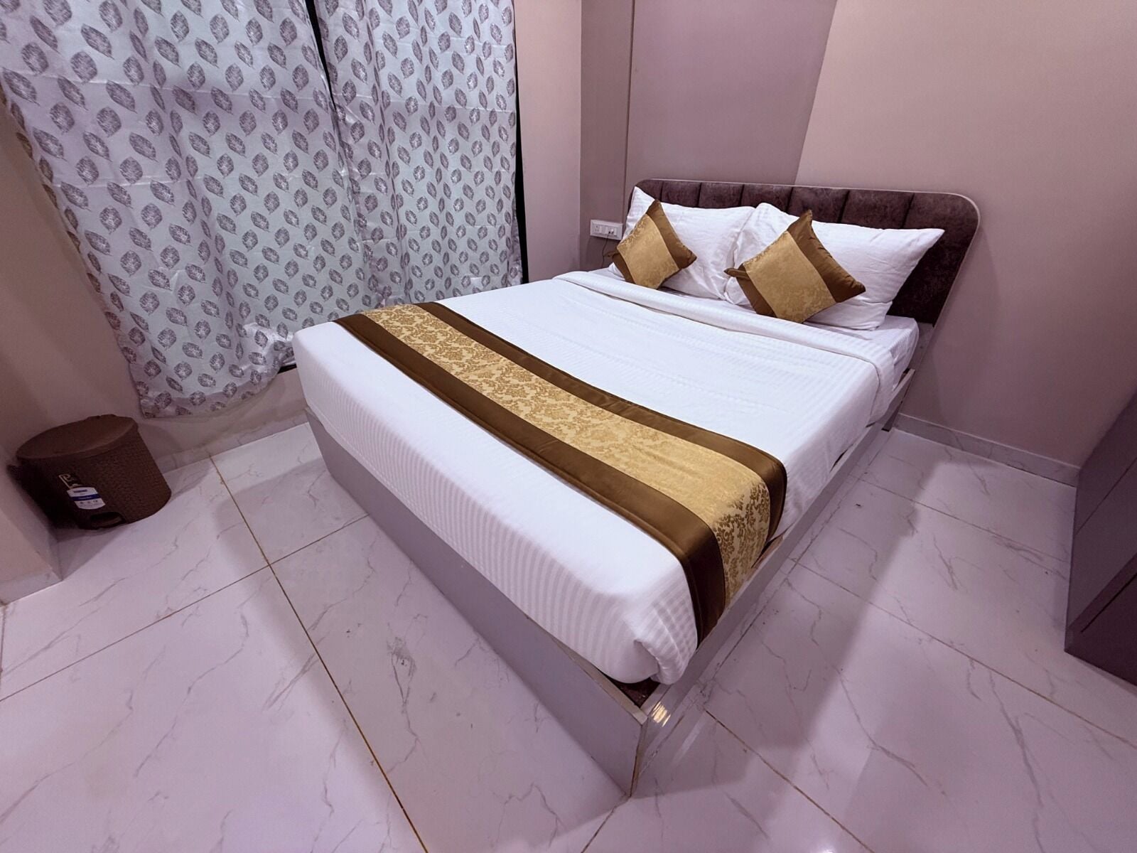 A neatly made bed with a patterned bedspread, a brown accent strip, and two pillows.