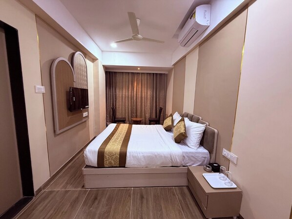 Una habitación de hotel con cama, mesita de noche, aire acondicionado y ventilador de techo, además de un espejo.