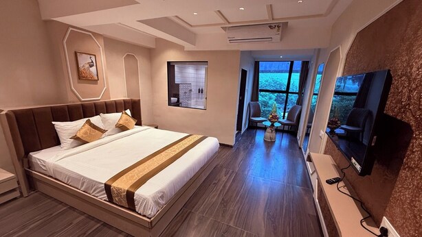 Una habitación de hotel moderna con una cama grande, un televisor, un escritorio y vistas al exterior.