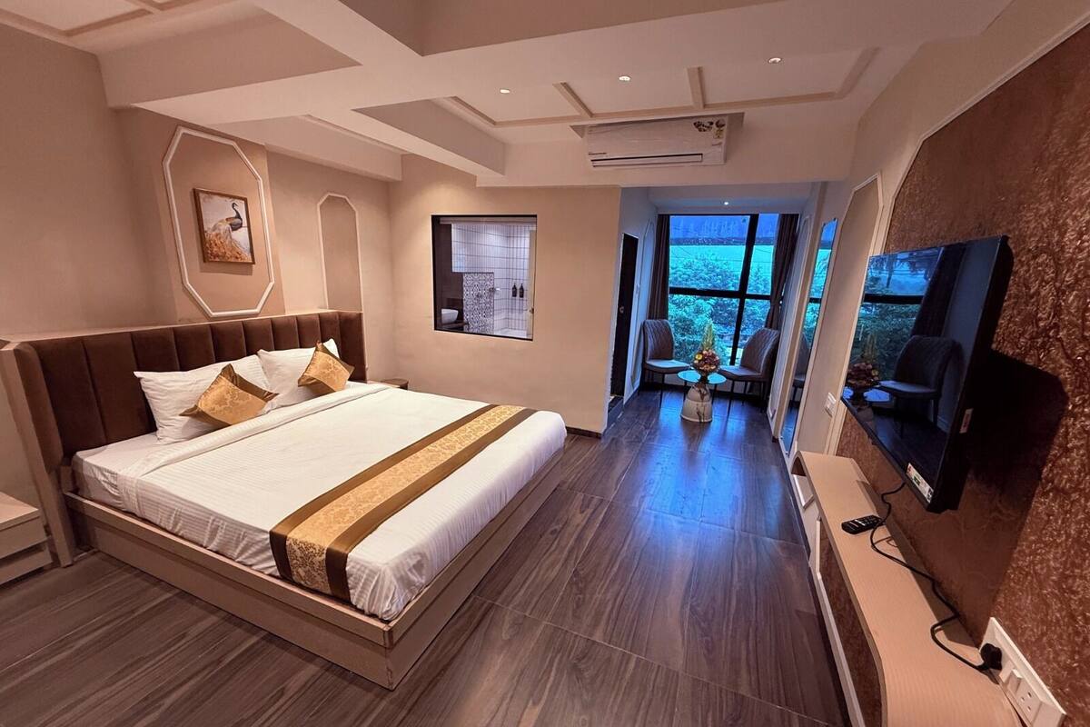 Una habitación de hotel moderna con una cama grande, un televisor, un escritorio y vistas al exterior.