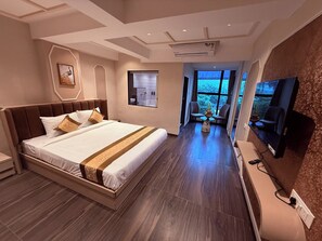 Una habitación de hotel moderna con una cama grande, un televisor, un escritorio y vistas al exterior.