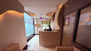 Un moderno vestíbulo de hotel con un mostrador de recepción, asientos cómodos y un amplio ventanal con vistas.