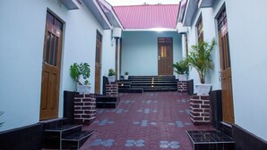 A covered walkway with steps leading to a door, flanked by potted plants and brick pillars. - SANAWARI LODGE (Arusha)